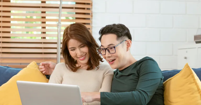 Couple interacting with laptop at their couch