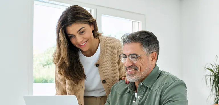 Couple interacting with laptop at their desk